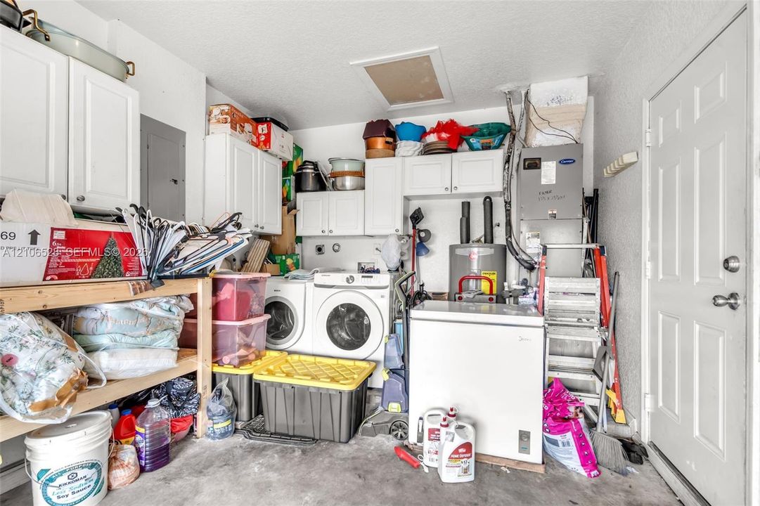 Utility space featuring white cabinetry, a dedicated laundry area, a water heater, and an HVAC system