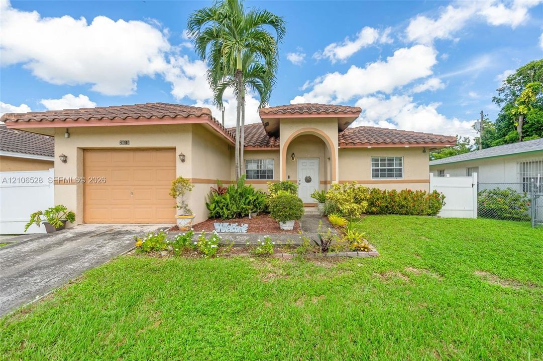 Stucco exterior featuring a tiled roof, arched entryway, single-car garage, and established landscaping