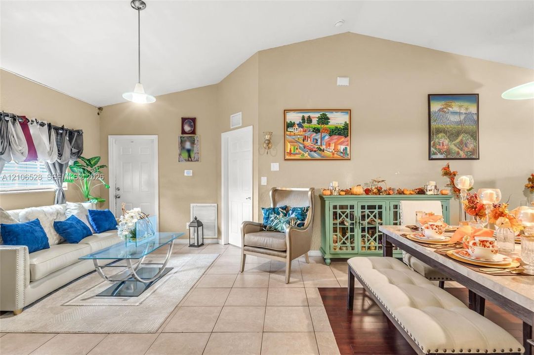 Vaulted ceilings, neutral wall tones, ceramic tile flooring, and a pendant light fixture