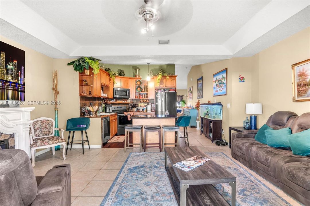 Tray ceiling, wood cabinetry, built-in fireplace, and kitchen island with seating