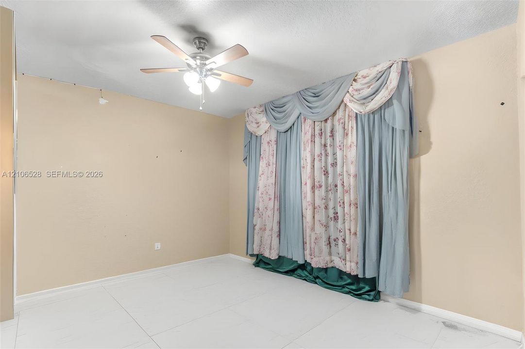Room featuring white tile flooring and a ceiling-mounted fan with integrated lighting