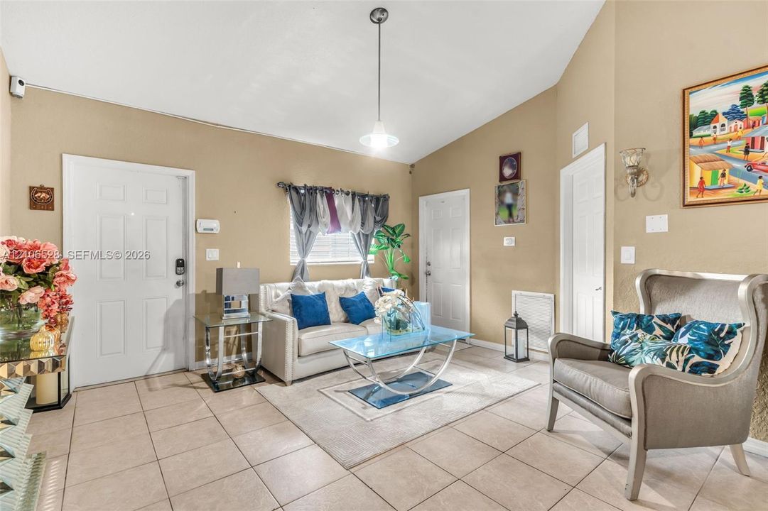 Vaulted ceilings, large-format tile flooring, and a central pendant light fixture