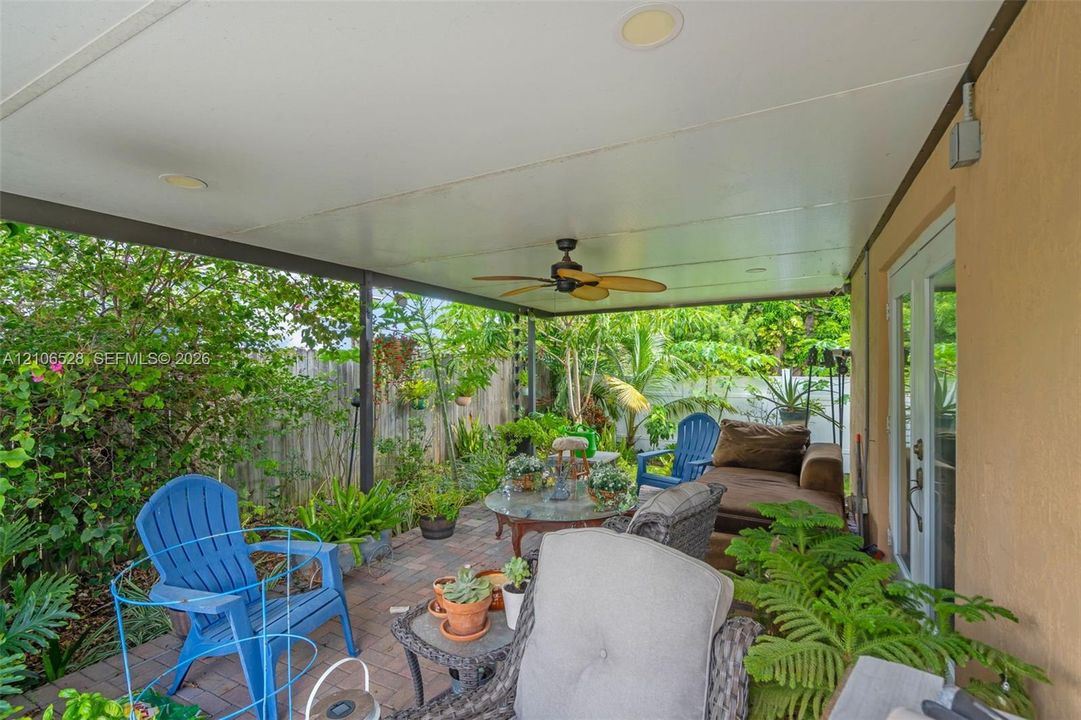 Covered outdoor patio featuring brick pavers, a ceiling-mounted fan, recessed lighting, and glass-paneled double doors