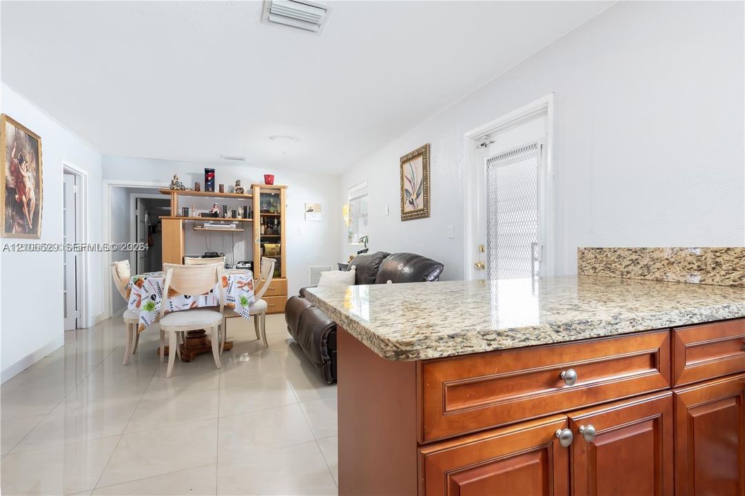 Kitchen featuring stone-finish countertops, warm-toned wood cabinetry, and neutral tile flooring