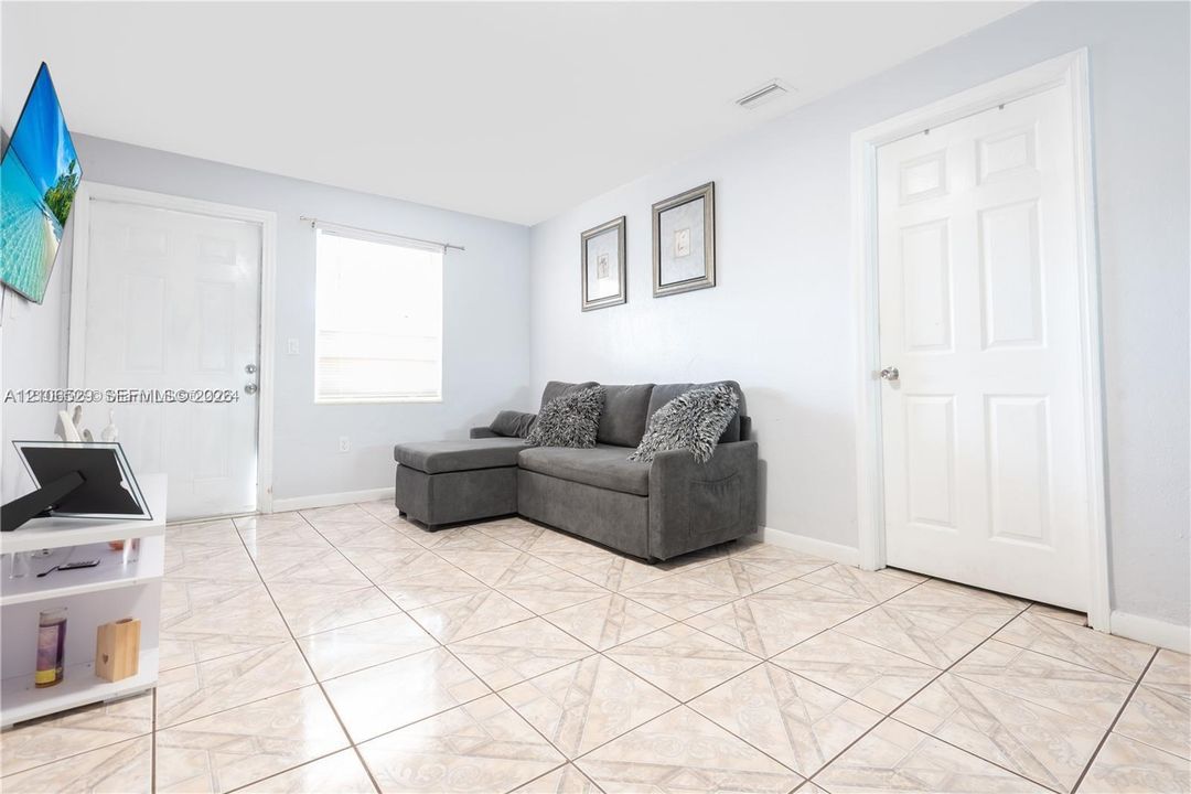 Interior space featuring diagonal-pattern ceramic tile flooring, neutral wall paint, two six-panel interior doors, and a double-hung window