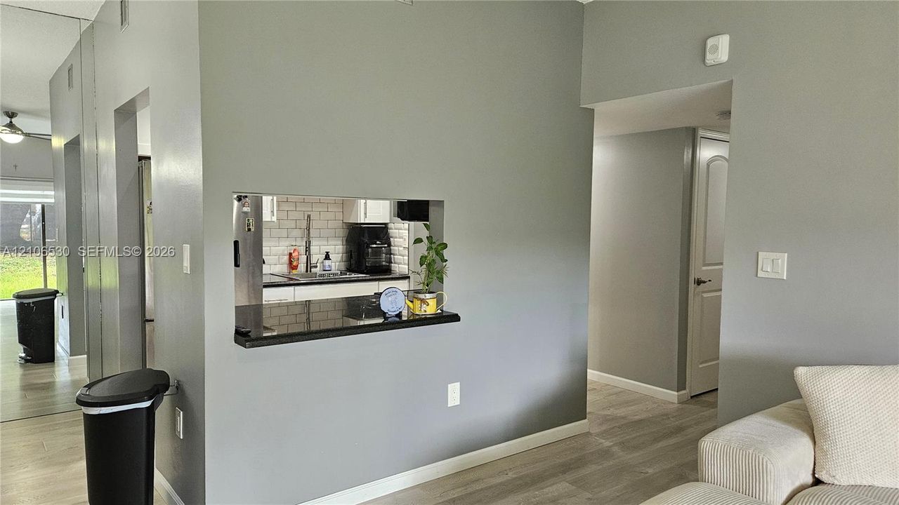 Pass-through opening featuring a dark stone countertop, neutral wall coloring, and light-toned wood-finish flooring