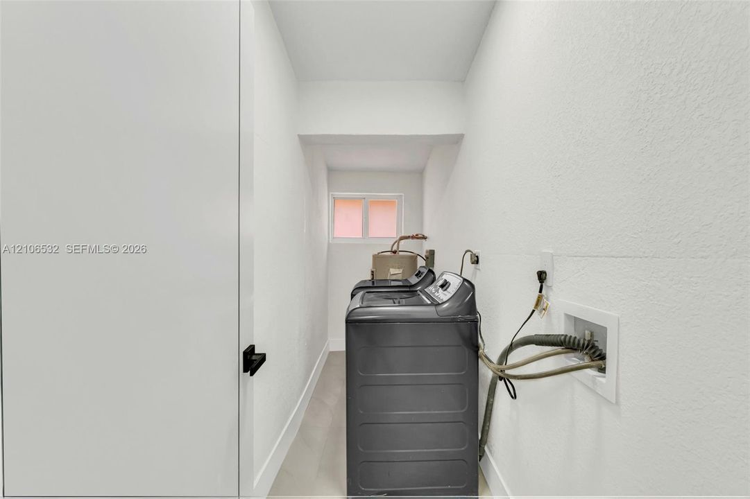 Utility room featuring neutral wall finishes, light-toned flooring, a window providing natural light, and dedicated hookups for laundry appliances