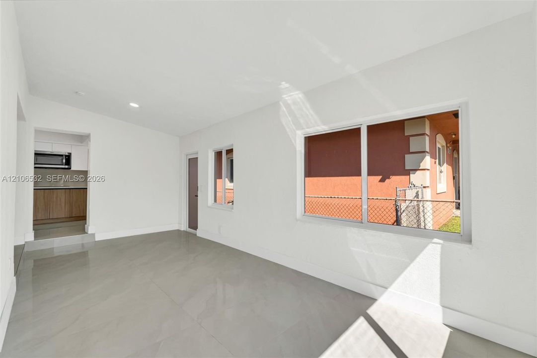 Neutral-toned tile flooring, recessed ceiling lighting, and large windows with aluminum frames