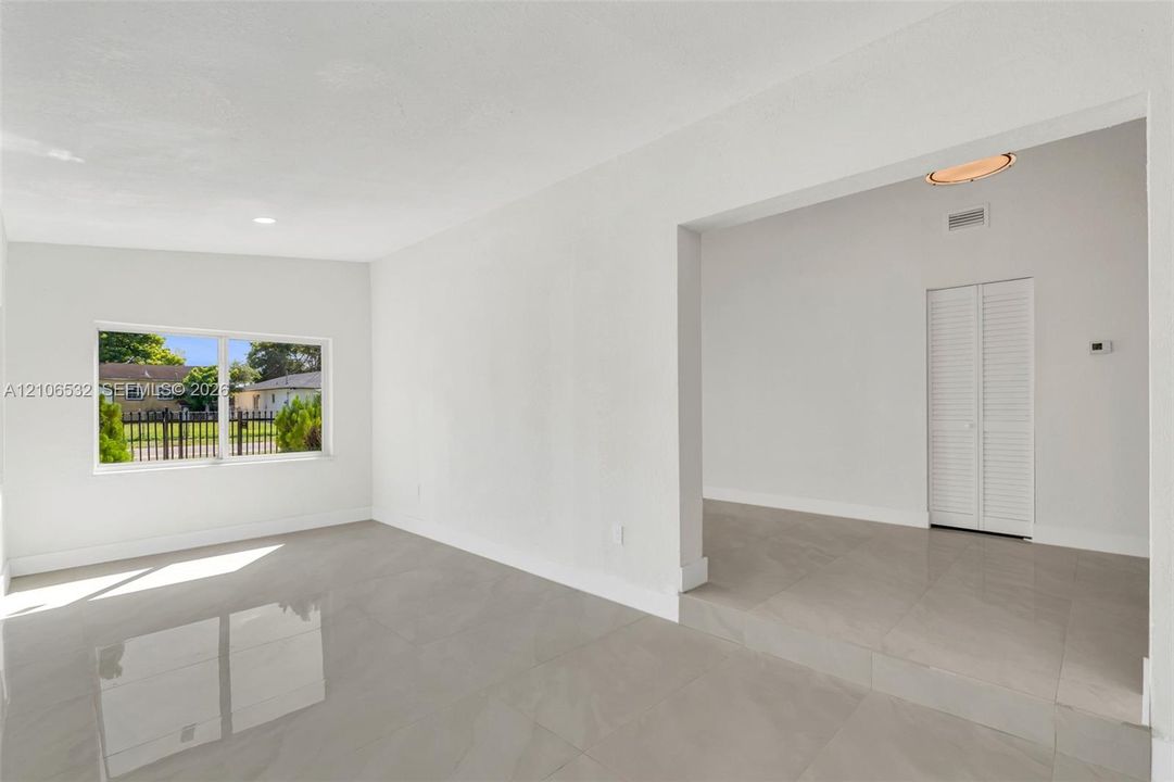 Large format tile flooring, white walls, recessed ceiling lighting, and louvered closet doors