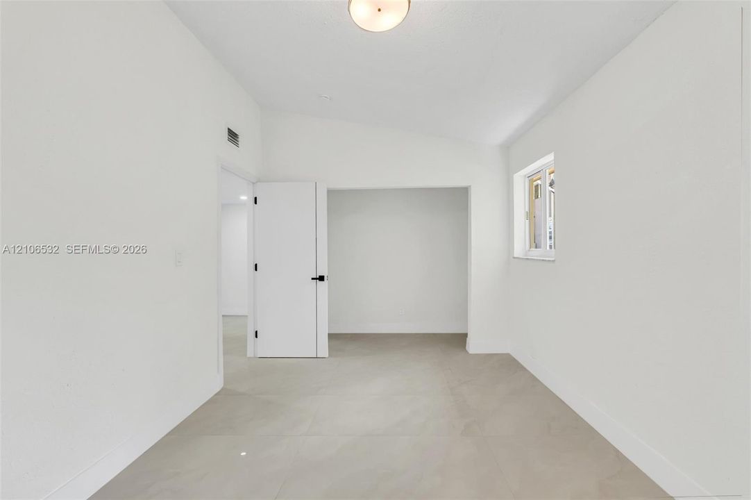Interior space featuring vaulted ceilings, light-tone tile flooring, and a flush-mount overhead light fixture