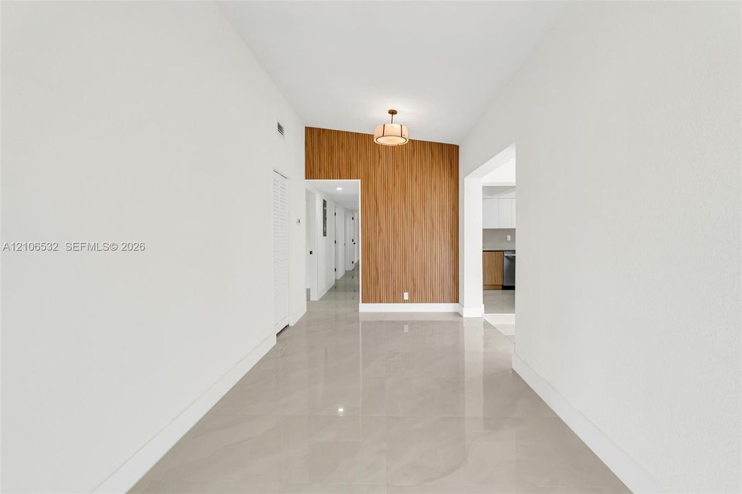 Entryway featuring polished large-format tile flooring, a wood-finish accent wall, and a multi-light drum pendant fixture