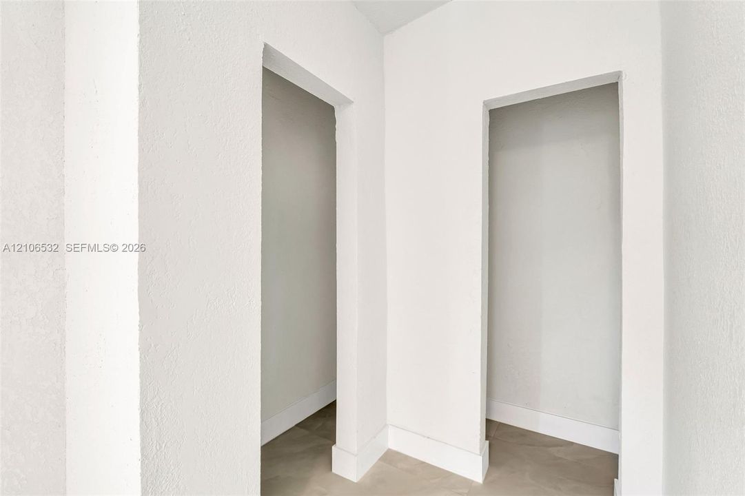Textured white wall finish, neutral tone flooring, and dual recessed openings