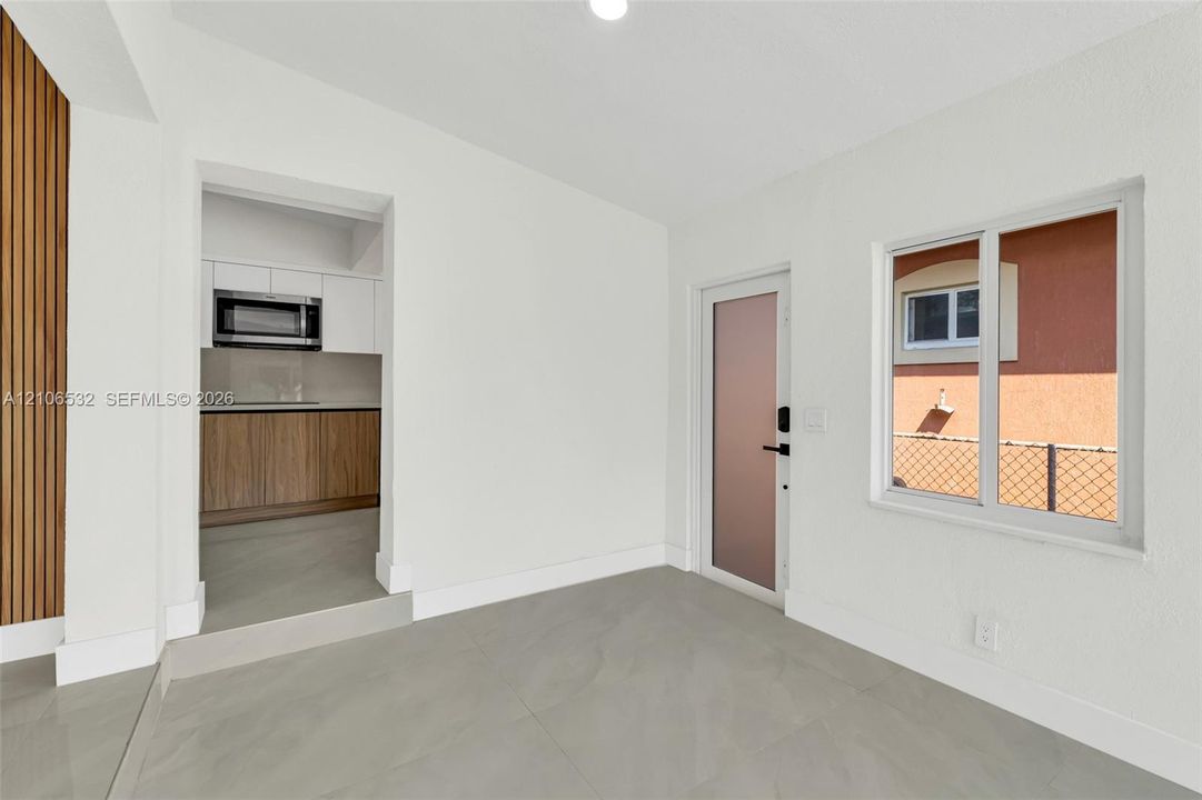 Neutral-toned large-format tile flooring, vertical wood-slat accent wall, and frosted glass entry door