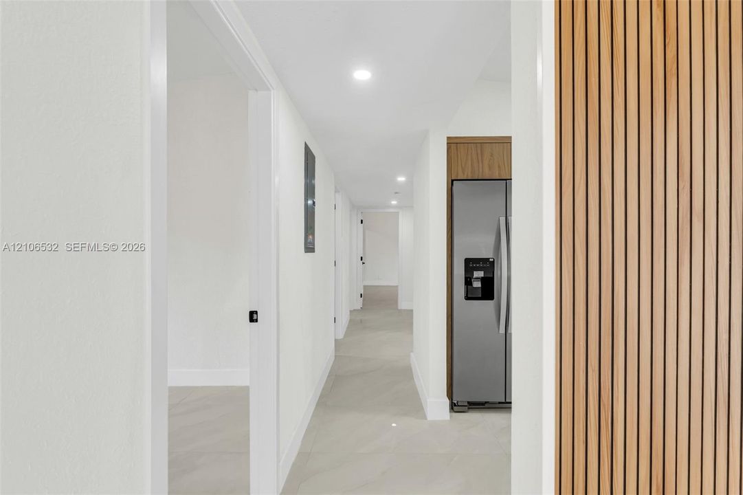Hallway featuring recessed lighting, large-format tile flooring, and a decorative vertical wood-slat accent wall