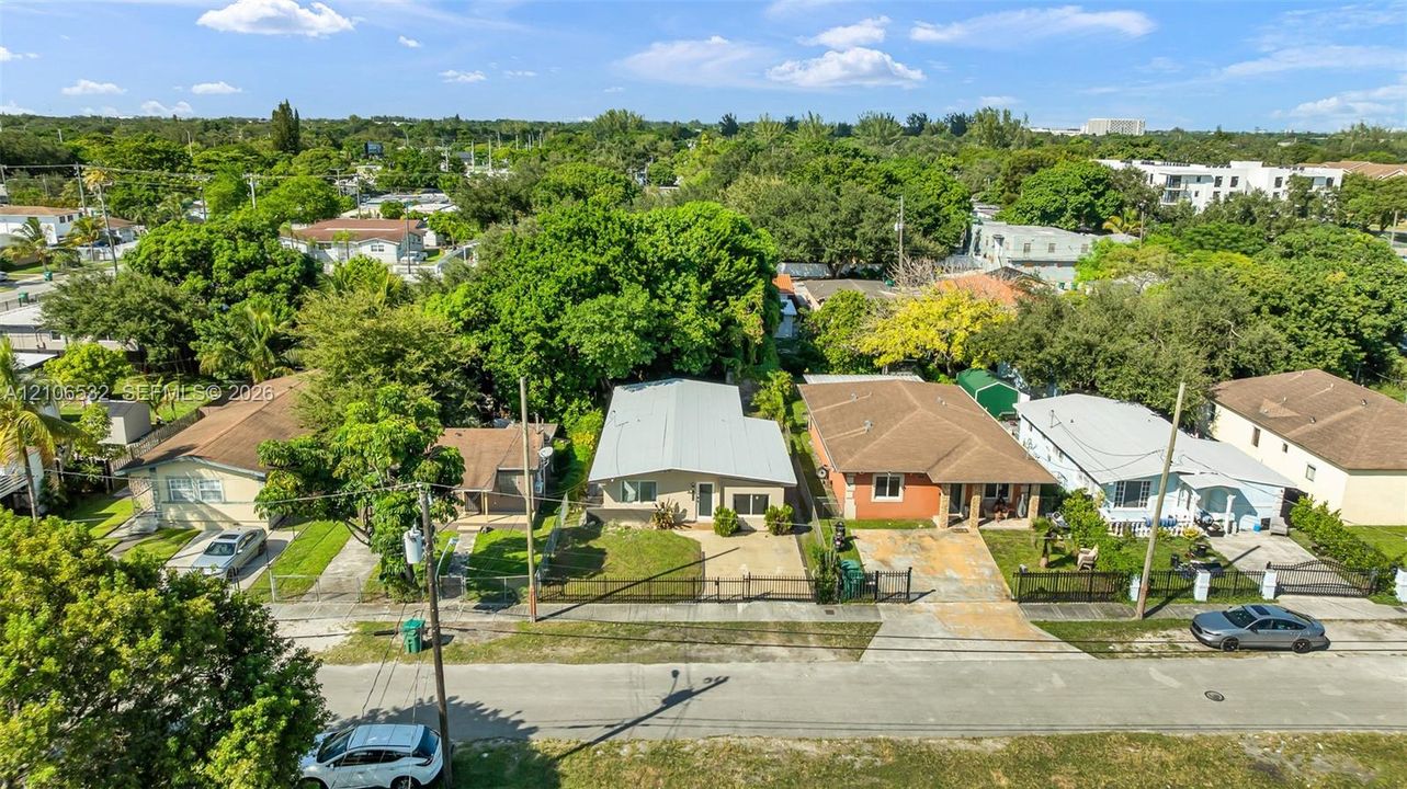 Aerial perspective of residential property featuring a metal roof, concrete driveway, and perimeter fencing