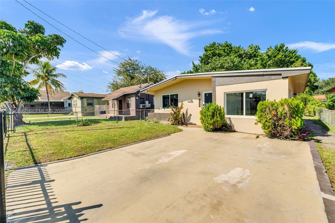 Single-story residence featuring a concrete driveway, exterior stucco finish, and chain-link perimeter fencing