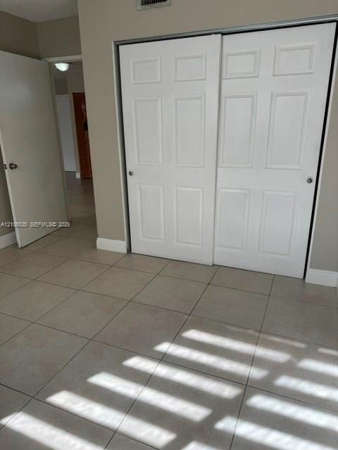 Neutral-toned ceramic tile flooring, two-panel interior passage door, and white six-panel sliding closet doors