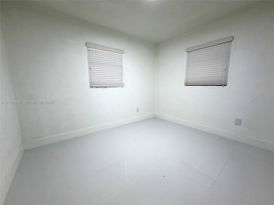Interior room featuring uniform wall finish, dual windows with integrated horizontal blinds, and smooth-finish flooring