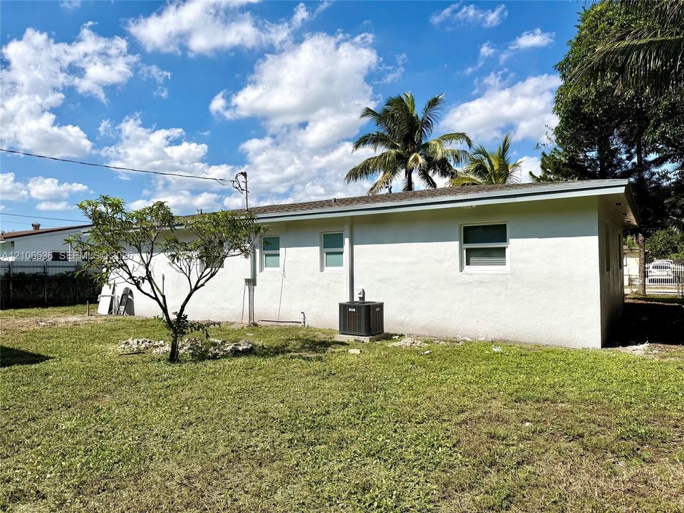 Exterior side elevation featuring white stucco siding, dual-pane windows, and an outdoor HVAC unit