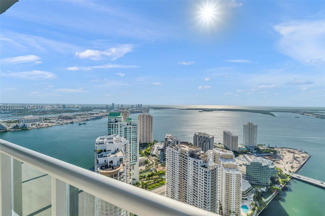 Elevated balcony featuring a white metal railing overlooking a coastal cityscape and open water