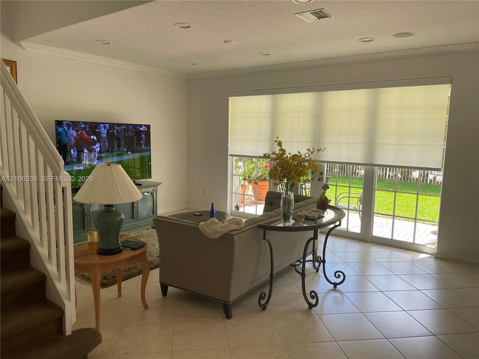 Open-concept interior featuring large-format tile flooring, recessed lighting, and expansive glass sliding doors with integrated shades