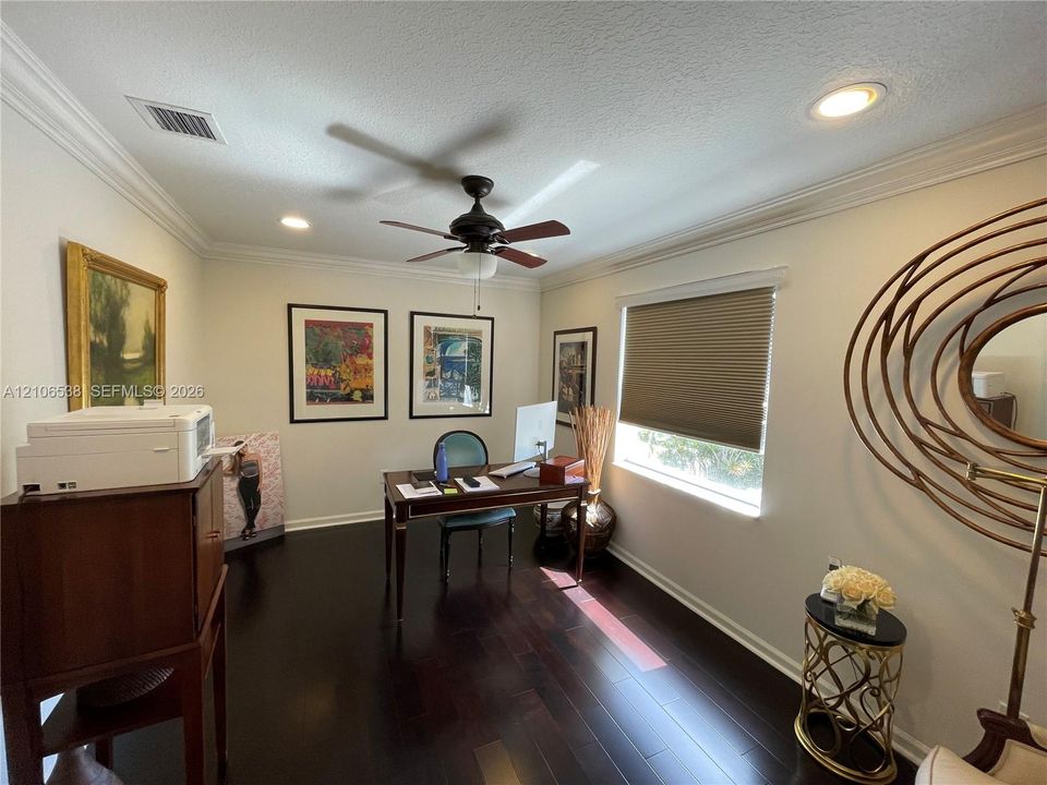 Room featuring dark wood-finish flooring, crown molding, a central ceiling fan with integrated lighting, and recessed overhead lighting