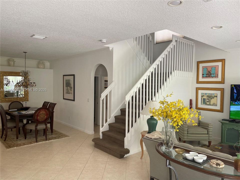 Open floor plan featuring tile flooring, an arched entryway, recessed lighting, and a staircase with a white wood railing