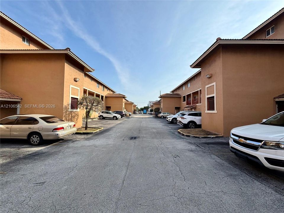 Stucco exterior complex featuring tiled roofing and designated surface parking areas