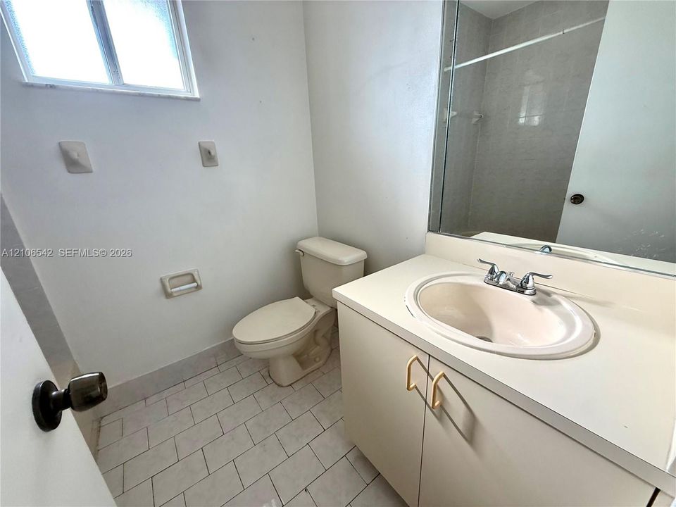 Bathroom featuring a vanity with an integrated basin, a large wall-mounted mirror, ceramic tile flooring, and a window