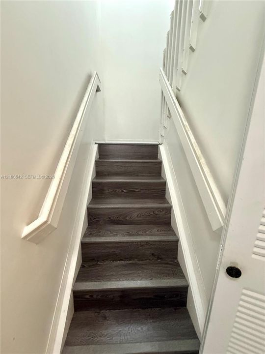 Staircase featuring wood-finish treads and dual white handrails