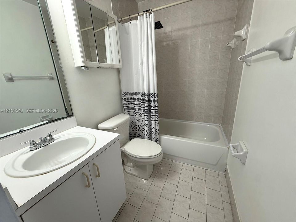 Bathroom featuring a white vanity cabinet, integrated sink, mirrored medicine cabinet, ceramic tile flooring, and a shower-tub combination with wall-mounted ceramic tile surround
