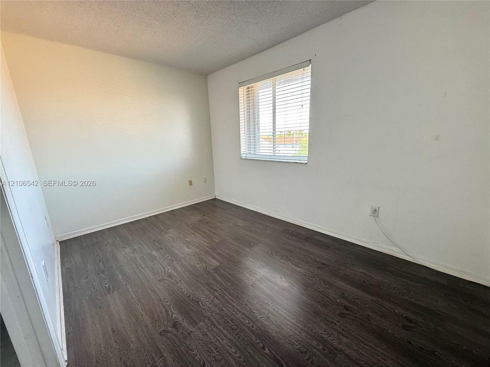 Neutral-toned interior space featuring wood-finish flooring and a window with horizontal blinds