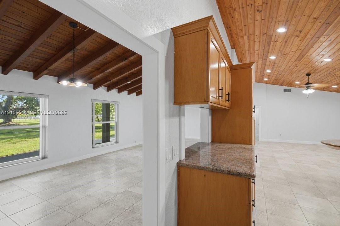 Wood-plank ceiling featuring exposed beams, tile flooring, built-in cabinetry, and recessed lighting