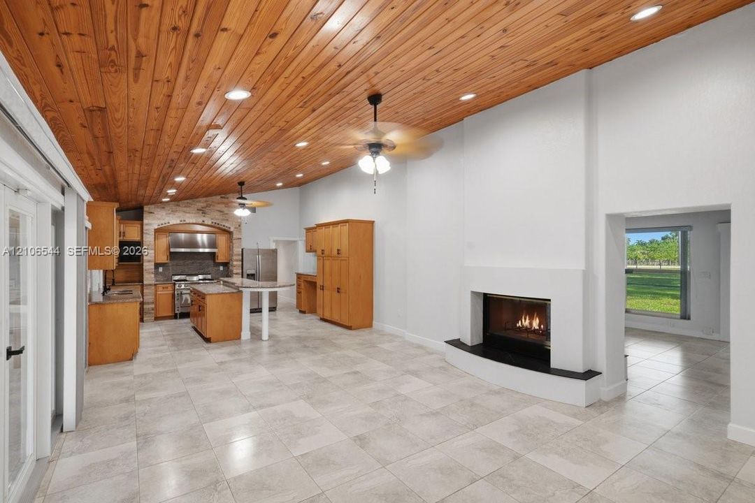 Vaulted ceilings with wood-plank finish, ceramic tile flooring, built-in fireplace with hearth, recessed lighting, and wooden cabinetry