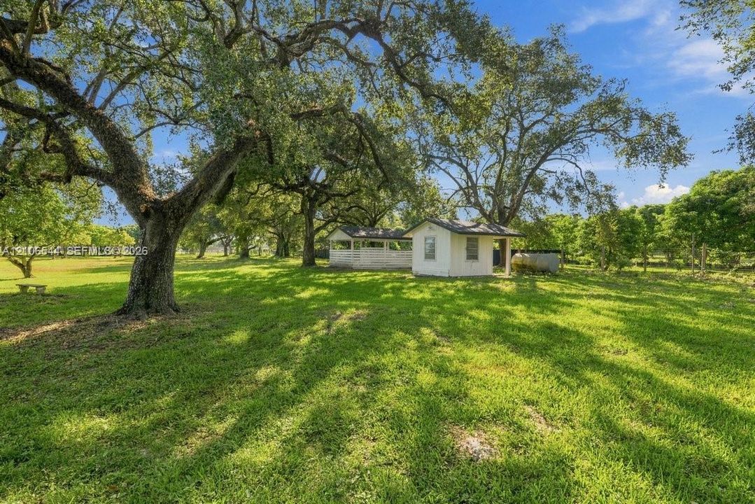 Expansive lot featuring mature hardwood trees and a detached structure with an attached gazebo