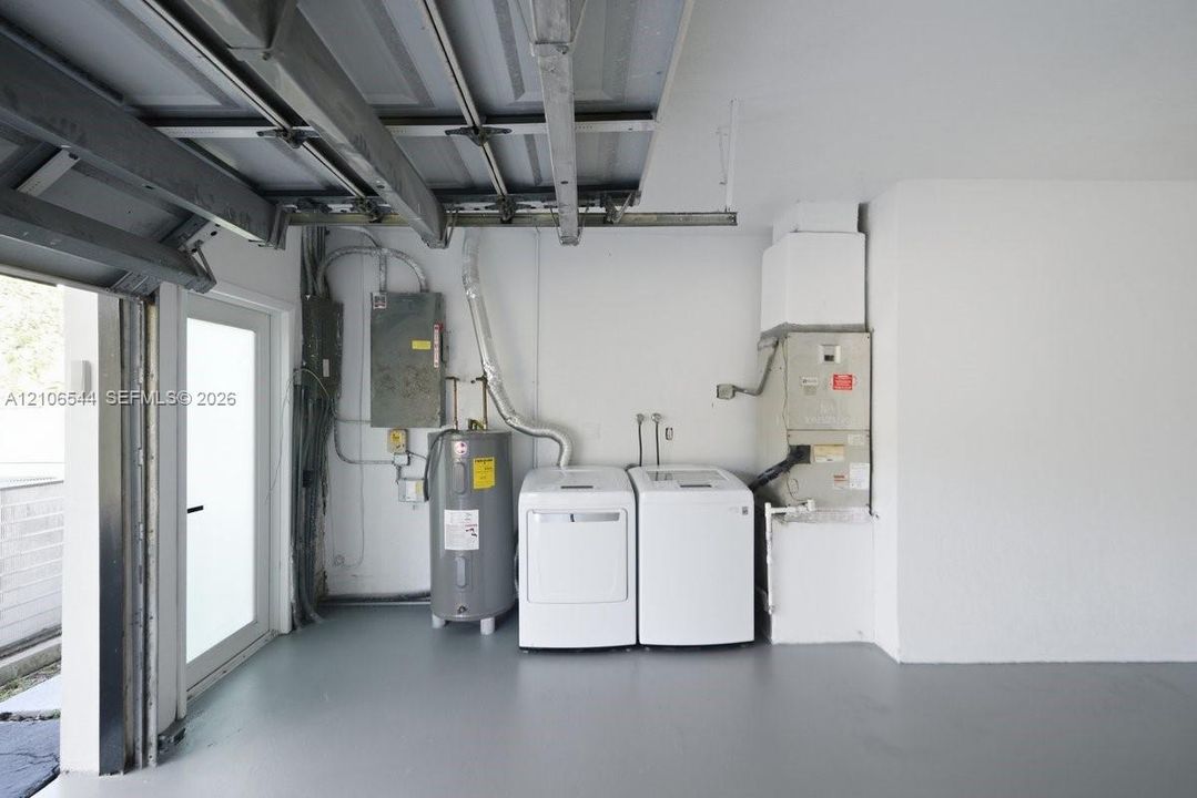 Garage space featuring a painted concrete floor, side-entry door, water heater, and mechanical systems