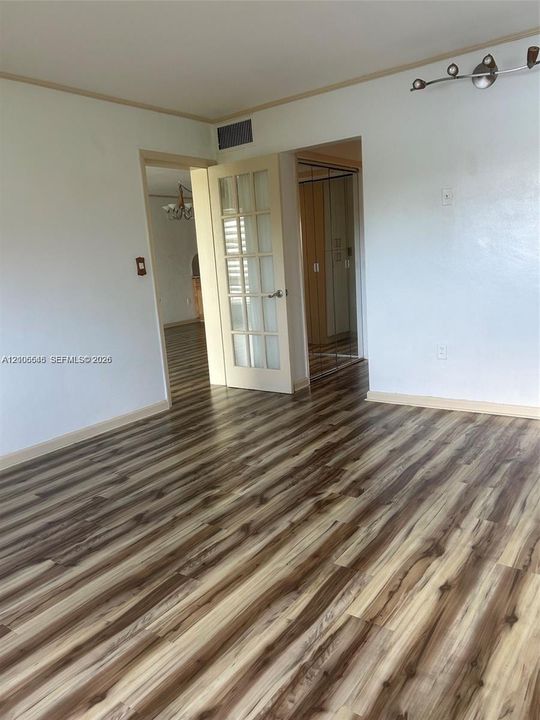 Wood-finish flooring, French-style paneled door with glass inserts, and multi-light track lighting fixture