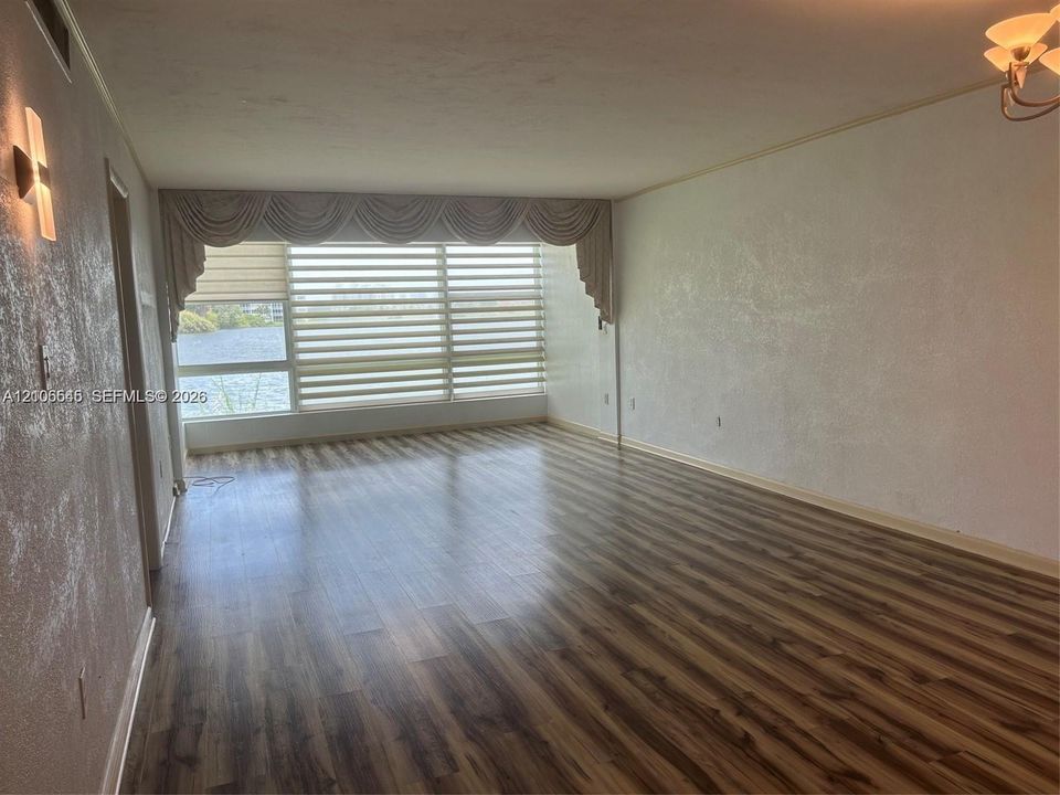Open-concept interior featuring wood-finish flooring, textured wall finishes, large picture windows, and integrated wall-mounted lighting