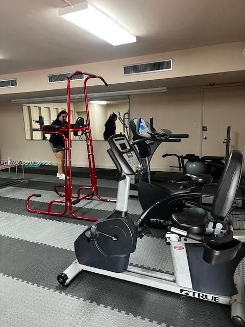 Multi-purpose room featuring wall-to-wall mirror installation, neutral painted walls, recessed ceiling lighting, and interlocking foam rubber flooring