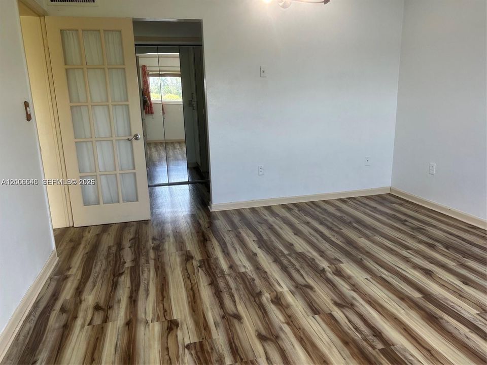 Wood-finish flooring, French-style glass-paneled door, and sliding mirrored closet doors