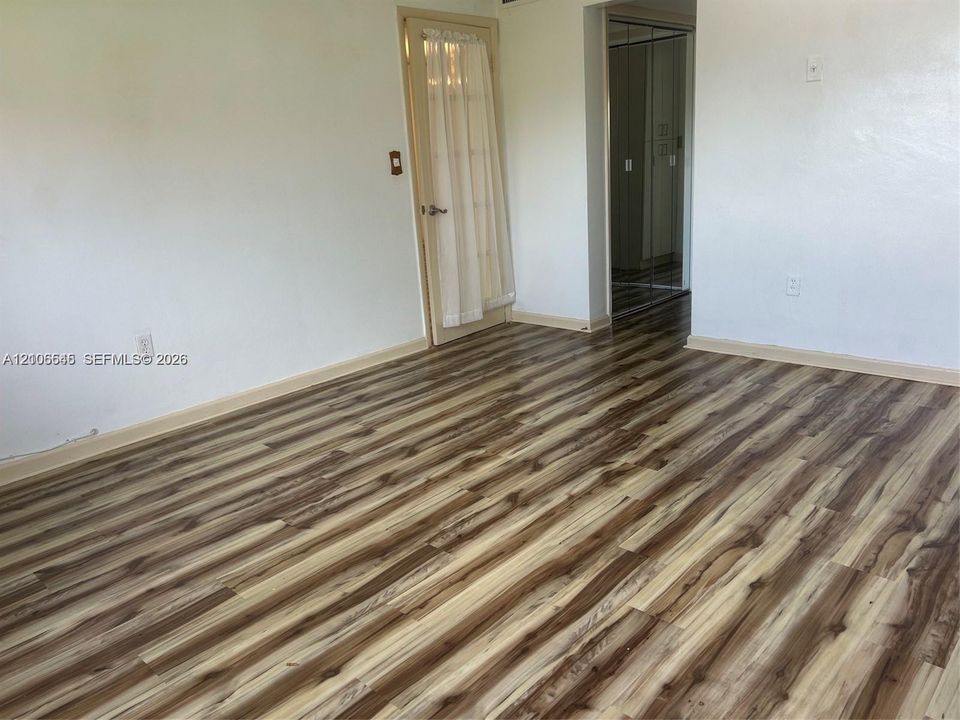 Wood-finish flooring, glass-panel entry door, and floor-to-ceiling mirrored closet doors