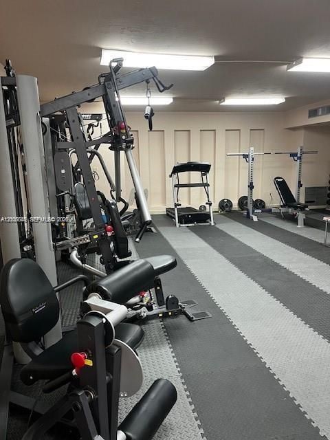 Interlocking rubberized flooring featuring a striped pattern, recessed wall paneling, and rectangular ceiling-mounted lighting