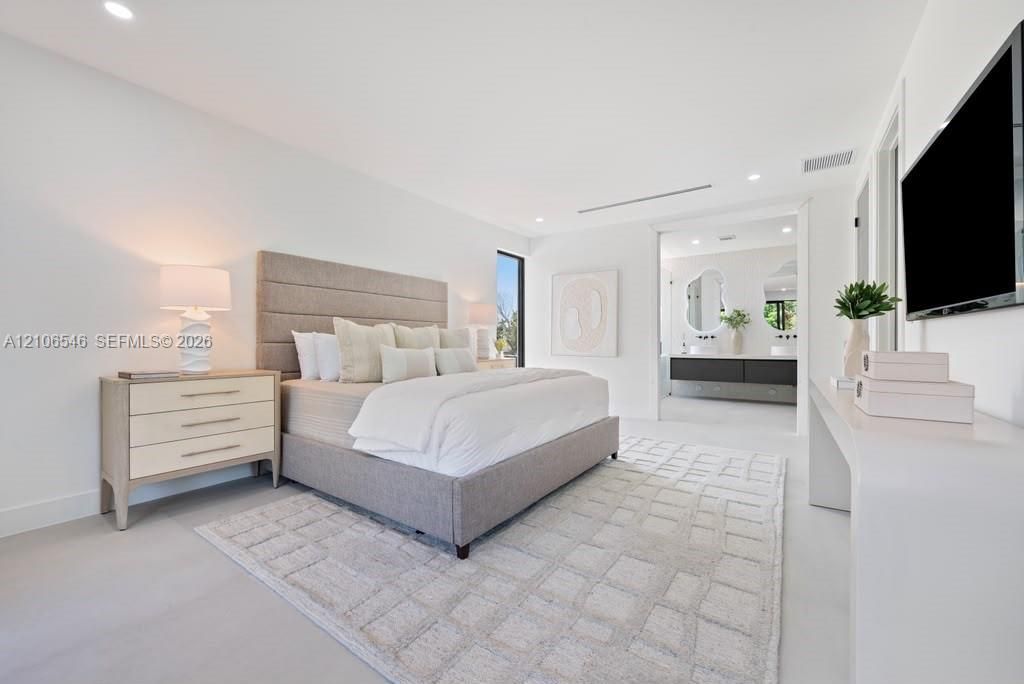 Spacious room featuring neutral tone-on-tone walls, smooth-finish flooring, recessed lighting, and a long built-in console table