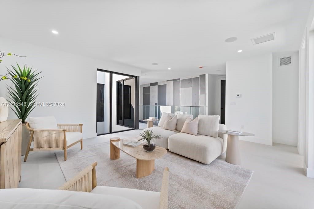 Minimalist interior featuring recessed lighting, a geometric accent wall with contrasting paneling, large-format smooth flooring, and a glass-panel stair railing