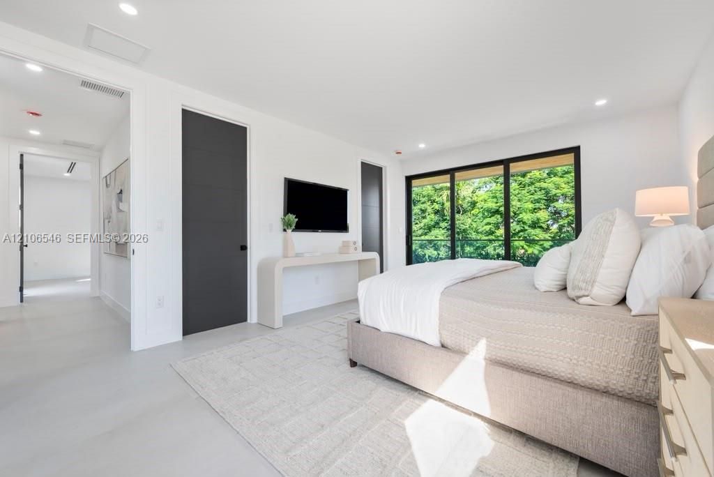 Recessed lighting, smooth-finish flooring, floor-to-ceiling sliding glass doors, and dark-finished doors with horizontal accents