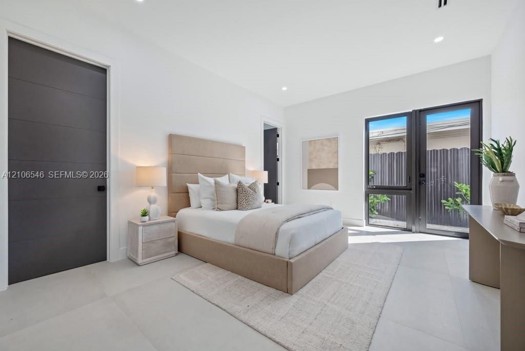 Neutral-toned room featuring expansive large-format floor tile, matte-finish horizontal panel doors, high ceilings, and floor-to-ceiling glass panel doors