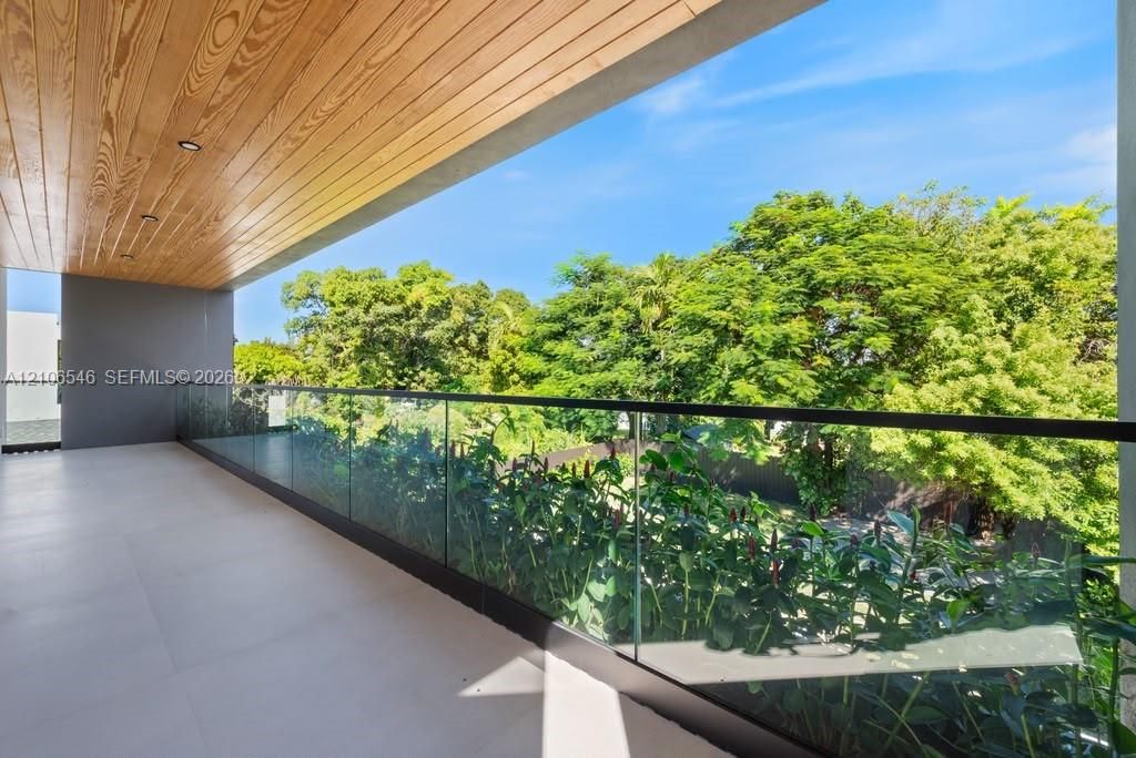 Covered balcony featuring wood-plank ceiling, recessed lighting, large-format tile flooring, and a frameless glass railing