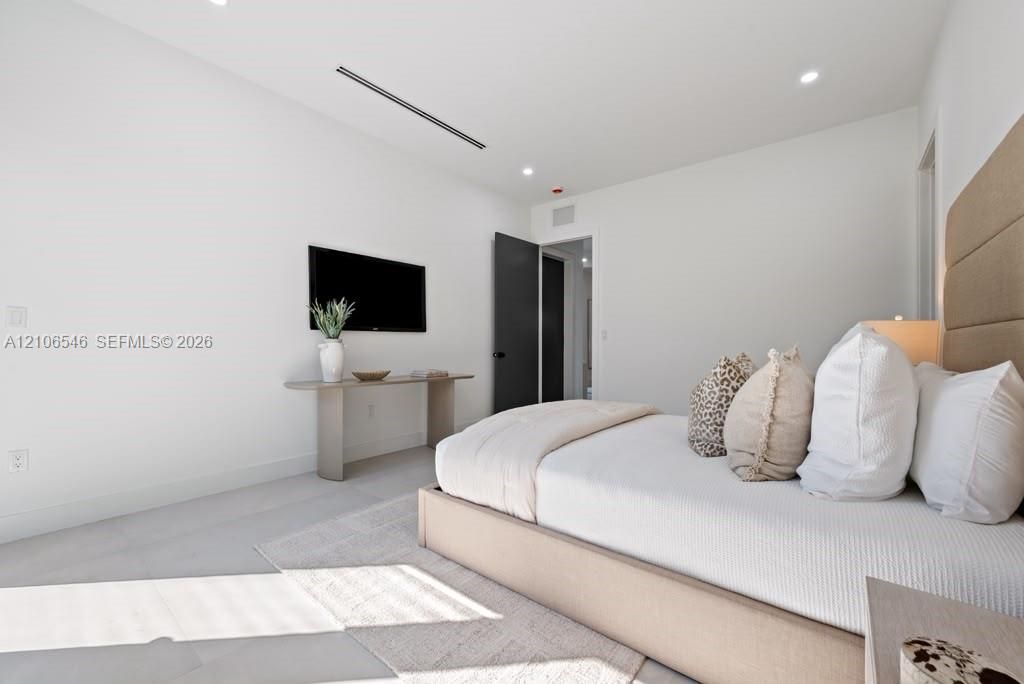 Neutral-toned room featuring recessed lighting, linear architectural ceiling detail, and dark-finished interior door