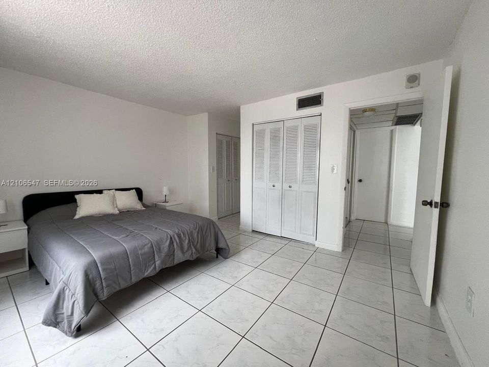 Room featuring white tile flooring, dual louvered-door closets, and a neutral color palette