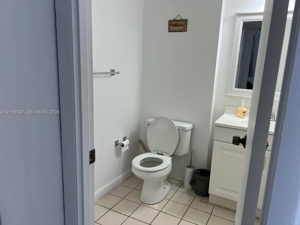 Bathroom featuring a white vanity cabinet with a integrated countertop, framed wall mirror, tiled flooring, and polished chrome hardware
